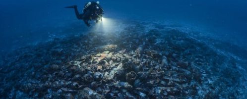 Diver evaluates the remains of the ship covered with hundreds of amphorae