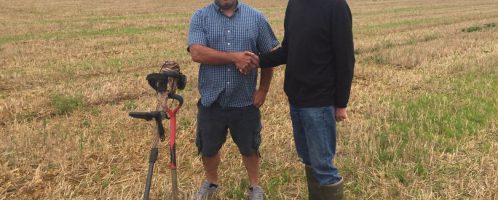 Historian Mike Smale shakes hands with the owner of a land where hundreds of Roman denarii have been found